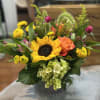 Golden Meadow is a cheerful, lush arrangement featuring bright sunflowers, and warm