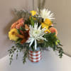 Fall favorites in a checkered vase including dahlias, lilies, and bunny tails