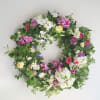 A wreath of seasonal flowers designed in a garden&rsquo;s embrace, reflecting continuity