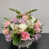 This charming arrangement features a soft mix of pastel blooms, including pink