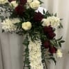 A foam cross filled with white flowers, lined with greenery.  Red