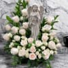 This serene sympathy arrangement features a graceful angel statue surrounded by an