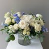 An elegant garden-style arrangement blending creamy white blooms with soft blue accents