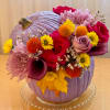 This eye-catching floral arrangement is designed in a bold lavender pumpkin vase