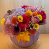 This eye-catching floral arrangement is designed in a bold lavender pumpkin vase