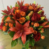 An elegant gathering vase filled with seasonal bright flowers such as asiatic