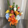 Mixed cut arrangement with yellow roses, blue hydrangea, orange alstroemeria, salmon roses