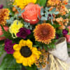 Glowing with autumn warmth, Sunset Harvest features radiant sunflowers, peach roses, bronze