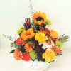A ceramic container with a lid, filled with fall mixed flowers and