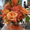 PEACH ROSES MUMS CARNS WITH LEAF ACCENTS AND GREENS IN A VASE