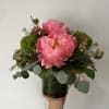 Seasonal peonies arranged with fillers and greens in a vase. 