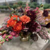 This floral arrangement is a stunning, autumn-inspired composition with a rich and