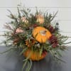 This adorable orange pumpkin keepsake container is filled with peach roses, blue