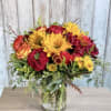 A bright and full arrangement filled with red garden roses, sunflowers, red