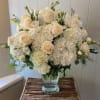 A dreamy arrangement of lush white hydrangea&#039;s, ivory roses, and soft seasonal