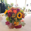 A delightful seasonal arrangement of fresh flowers and fall accents, masterfully arranged