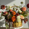 A rustic autumn basket overflowing with warm seasonal blooms in shades of