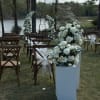 A serene lakeside ceremony setup featuring elegant floral pillars and a romantic