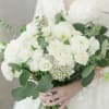A timeless bridal bouquet featuring white ranunculus, spray roses, delicate berries, and