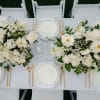 A refined wedding tablescape adorned with lush 2 arrangements of white roses