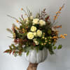 Seasonal flowers arranged into a white pumpkin with fillers and greens. 