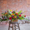 Autumnal flowers are artfully arranged in a rectangular woven wicker basket. Sunflowers