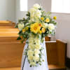 A graceful floral cross designed with soft ivory blooms and radiant yellow
