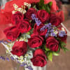 One dozen (or more) red roses arranged in a hand tied bouquet