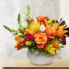 This unique design includes coral colored roses, pin cushion protea, orange lily