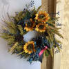 A medium sized wreath with sunflowers and blue ribbon 
