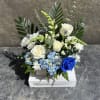 White roses, chrysanthemums, snapdragon, hydrangea, with other filler blooms, and foliage. 