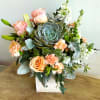 Peaceful yet energizing, this unforgettable arrangement of desert-hued blooms and succulents in