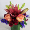 A colorful variety of flowers arranged in a short cylinder or square