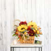 Send sunshine with a basket of sunflowers, rich-toned chrysanthemums, autumn leaves and