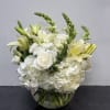 A graceful all-white arrangement featuring lush hydrangeas, classic roses, and elegant lilies