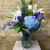 This arrangement contains delphinium, bells of ireland, asiatic lilies, hydrangea, and other