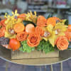 Stunning centerpiece of orange and yellows including Hydrangeas, Roses, Orchids and more