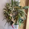 A medium sized wreath with cream colored silks and greenery 