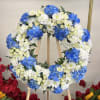 This serene funeral wreath features white roses and cushion blooms paired with