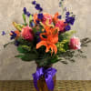 Type of Flowers: Orange Lilies, Orange Roses, Purple Larkspur, and greens in