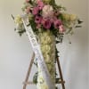 Featuring a mix of roses, ranunculus, and white pom poms, this cross