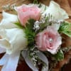This pink and white rose corsage features spray roses and filler.