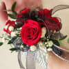 This wrist corsage is made up of red spray roses, filler and