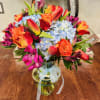 A bouquet with orange tulips, orange roses, blue hydrangeas, and pink asters