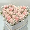 A romantic heart-shaped box filled with soft pink roses and accented with
