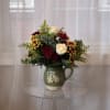 This charming floral arrangement is designed in a rustic green ceramic pitcher