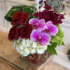 A beautifully modern, short compact arrangement featuring rich red roses, fragrant stock