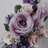 This corsage features pastel pink and lavender spray roses on a wristlet