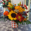 Orange and white plaid glass cylinder vase filled with colorful blooms of