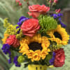 A VIBRANT SUNFLOWER AND MIXED BOUQUET IN A HAPPY FACE FOOD SAFE